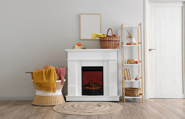 Interior of light room with fireplace, autumn decor and shelf unit