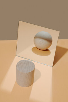 cylinder in front of a mirror reflects the image of a ball