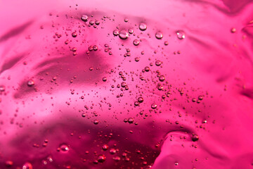 Vibrant red liquid with bubbles. Abstract cosmetic textured background