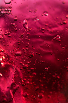 Vibrant red liquid with bubbles. Abstract cosmetic textured background