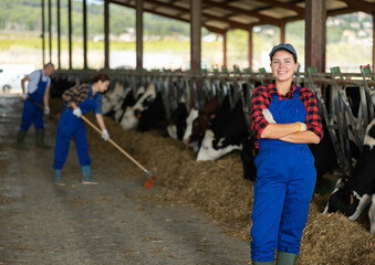 Young female farmer worker in cow pen on cattle farm