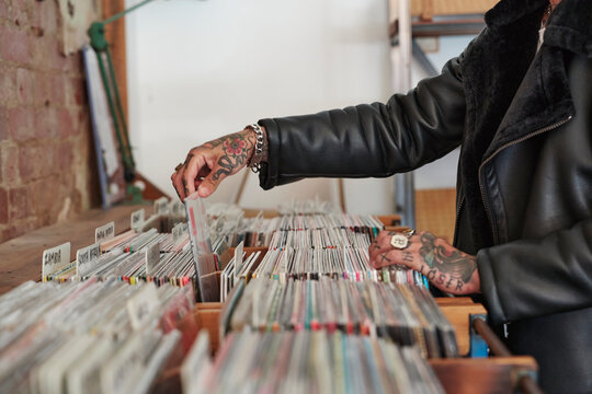 Person browsing through vinyl records at a local music store