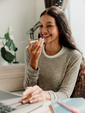 Smiling Woman Using Voice Command on Smartphone at Home