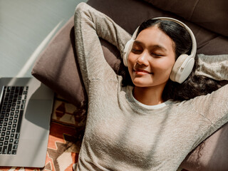 Peaceful Woman Relaxing With Headphones and Laptop at Home