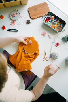 Person hand embroidering a floral design with colorful threads

