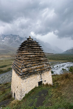 Ancient stone crypt in Dargavs under stormy sky

