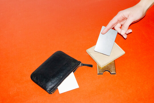 Wallets and hand holding a credit card with hard direct flashlight