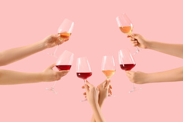 Female hands holding glasses of different wine on pink background
