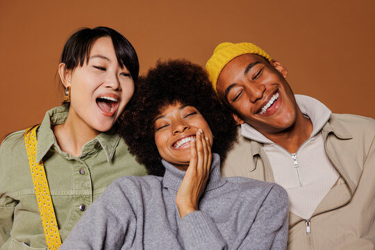 Three young adults laughing together in studio