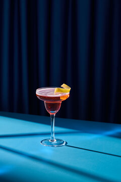 Elegant Cocktail Glass With Citrus Garnish Against Blue Background