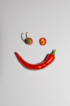 Photo of hot, red and spicy chili smiley grey background with shadow