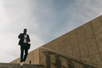 Businessman walking down stairs checking watch