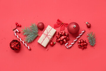 Beautiful composition with Christmas balls, candy canes and fir branches on red background