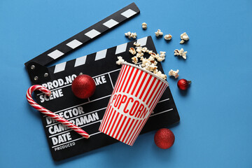 Bucket of popcorn, movie clapper and Christmas decor on blue background