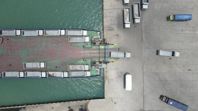 top down view truck loading into a car carrier ship. Car ferry leaving docks fully loaded.