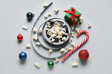 Scattered popcorn, film reel, gift box, candy cane and Christmas decor on white background