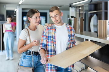 Positive interested young man and woman exploring various wood-look eco-friendly laminate...