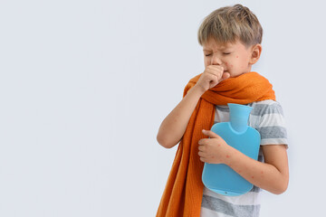 Little boy ill with chickenpox and hot water bottle coughing on white background