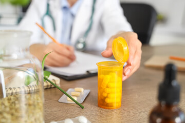Female homeopathic doctor with pills working at table in office, closeup