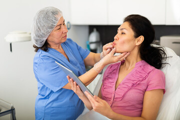 Doctor beautician discussing with woman cosmetological procedure in clinic