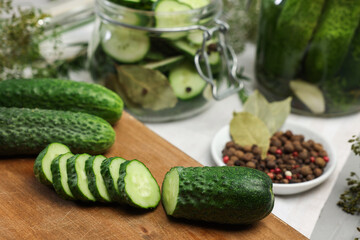 Board with fresh cut cucumber and spices on light table, closeup. Preparation for pickling