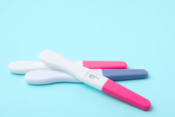 Pregnancy tests on light blue background, closeup