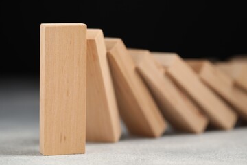 Domino effect. Wooden blocks falling on grey table, closeup