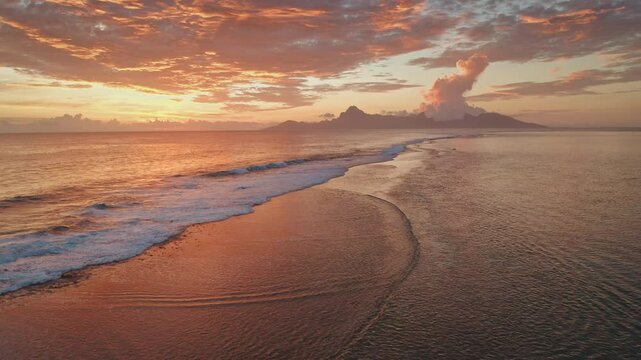 Tropical island beach shore at sunrise, beautiful bright color sea sunset, waves gently rolling coastline, sky and water in vibrant shades of orange and pink. Nature paradise, summer travel background