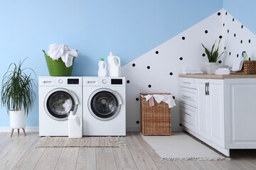 Interior of laundry room with washing machines, detergents and baskets