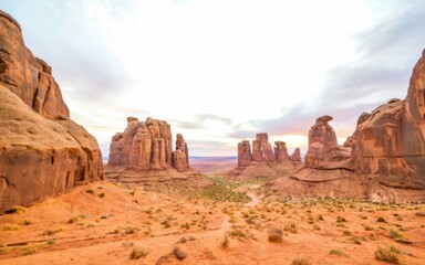 Fototapeta premium Canyonlands Majesty: A breathtaking panoramic view of towering sandstone formations under a soft, sunrise sky. The textures and colors evoke a sense of ancient wonder and timeless beauty. 