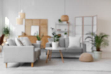 Blurred view of living room with grey sofas, folding screens and plants