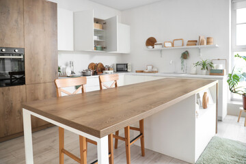 Interior of light kitchen with table, counters and cupboards