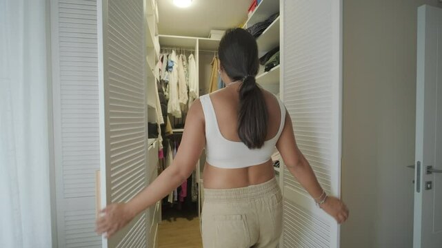 A pregnant woman standing near a mirror at home, putting on clothes. The scene reflects self-care, maternity, and everyday life in a warm and personal setting