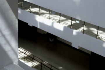 The quiet minimalist white multi-storey buiding during the day with bright light from the trasparent roof