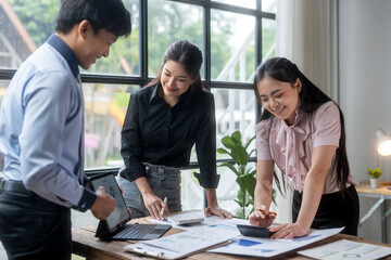 Fototapeta premium Three women are sitting at a table with a laptop and a calculator