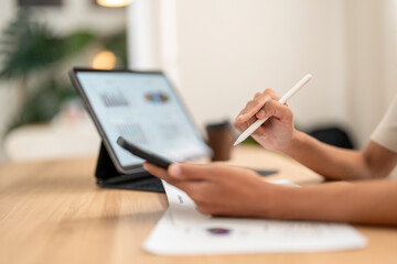 Businesswoman analyzing financial data on tablet and smartphone using stylus