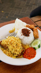 Nasi Ayam Penyet famous traditional Malaysian Indonesian food serve with spicy roasted chicken, slices of cucumber and sambal belacan.