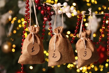 Christmas advent calendar with gifts and decor hanging on blurred background, closeup