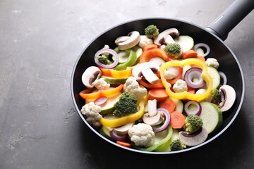 Frying pan with mix of vegetables and mushrooms on grey table, closeup. Space for text