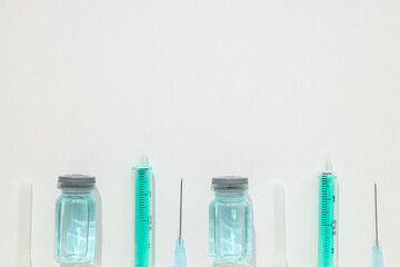 Glass medical bottles with vaccine and syringes on white background, space for text