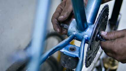 Unrecognizable man fixing blue bike in bicycle mechanics workshop