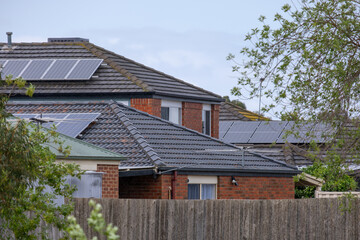 Modern suburban houses or Australian homes with solar panels installed on a tiled roof during an...