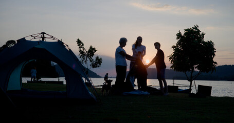 Candid Shot of Family Campers with Grandparent, Mother, and Son Setting Up Tent in Nature Reserve - Weekend Teamwork Bonding with activity together in nature in the evening at Twilight time.