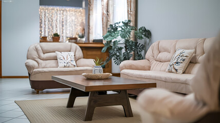 Cozy living room featuring soft beige sofas, a wooden coffee table, and indoor plants. Bright natural light filters through sheer curtains, creating a warm and inviting atmosphere.