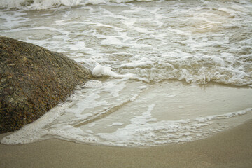 A beautiful seascape with white foamy waves crashing on beach sand