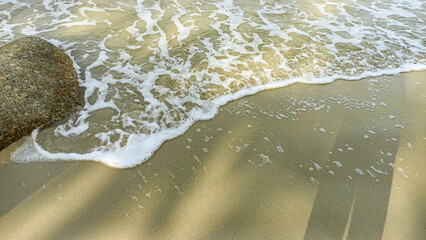 A beautiful seascape with white foamy waves crashing on beach sand