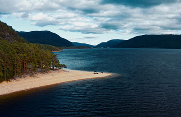 A Serene Lakeside Scene Featuring a Beautiful Mountainous Backdrop and Sandy Shoreline