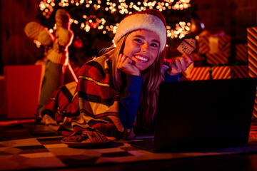 Full length photo of young female watch movie eat cookie wear christmas garment garland light cozy x-mas party decoration interior indoors