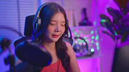 Asian audio DJ woman talking on microphone to broadcasting in neon room.