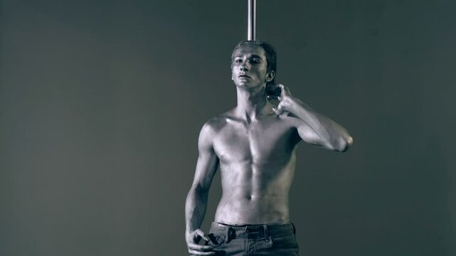 Strip dancer. Sexy man on pole dance. Pole dancer on pylon. Shirtless strong sexy man dancing. Male flexibility, and grace. Guy performing trick on pole. Male athlete doing acrobatic trick.